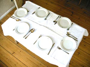Bild gedecktem Tisch auf dem f&uuml; jeden Teller Messer und Gabel da sind, aber nicht f&uuml; jeden Teller ein L&ouml;ffel.